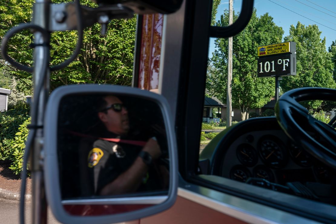 Cody Miller, with the Salem Fire Department, waits near a digital sign tracking the day's temperatures as parts of Oregon bake in a heat wave Saturday.