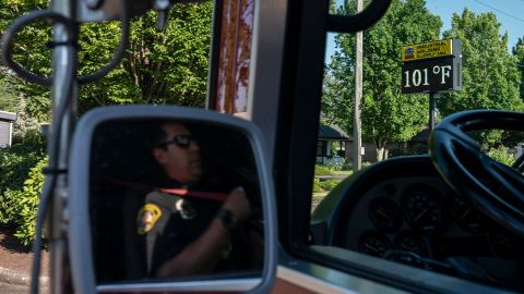 Cody Miller, with the Salem Fire Department, waits near a digital sign tracking the day's temperatures as parts of Oregon bake in a heat wave Saturday.