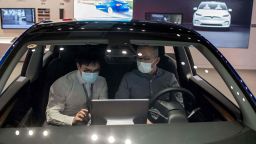 A man (R) sits inside of a Tesla car Model 3 as a vendor talks to him at a Tesla shop inside of a shopping Mall in Beijing on May 26, 2021. (Photo by NICOLAS ASFOURI / AFP) (Photo by NICOLAS ASFOURI/AFP via Getty Images)