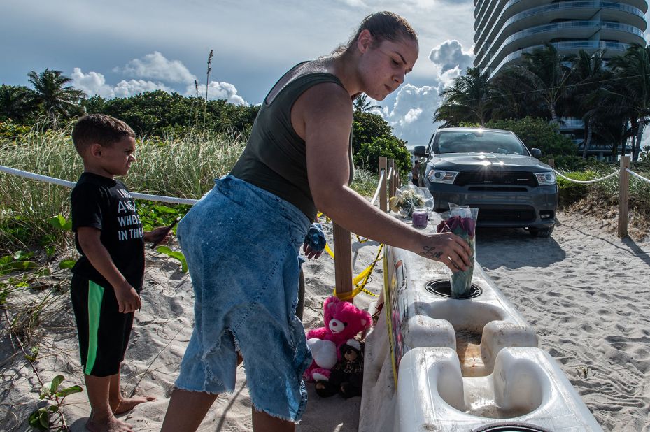 A woman puts flowers in a barricade as she pays her respects near the building.