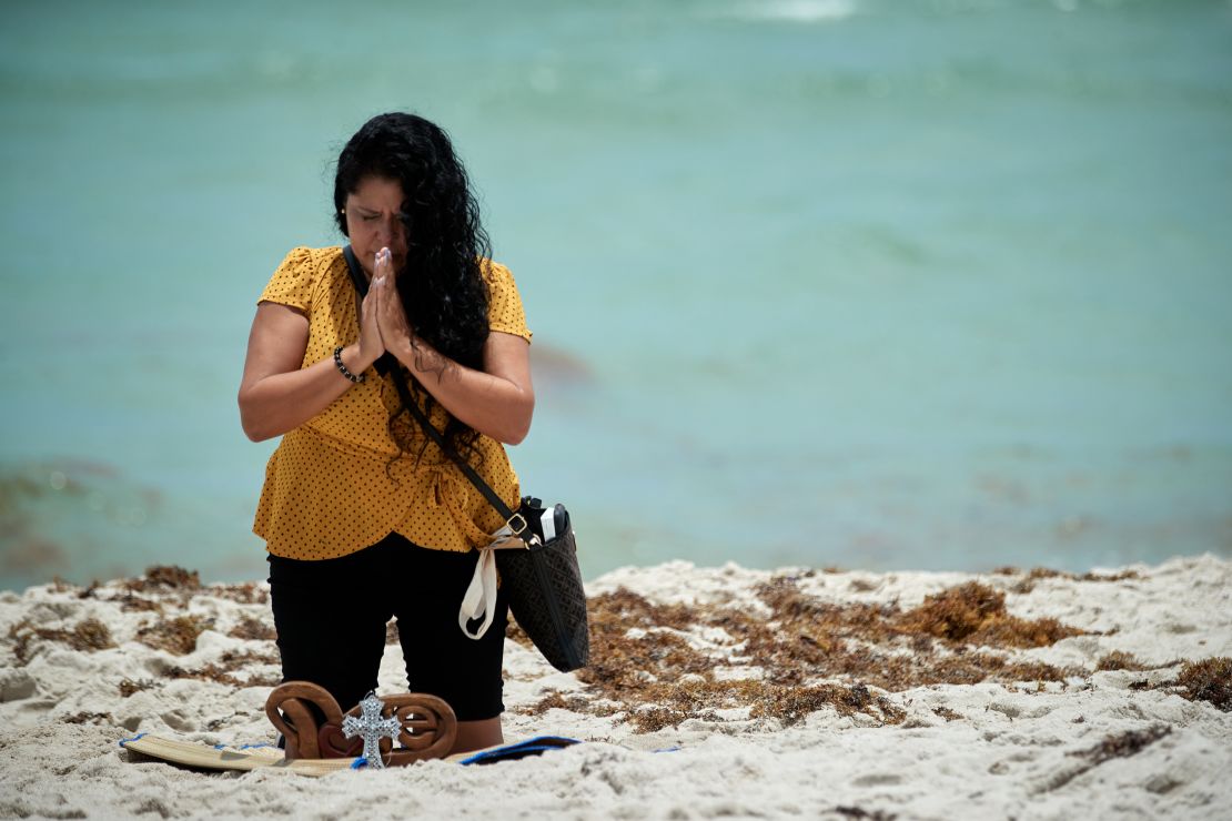 Luz Zenedith prays for the victims on the eastern beach side of of the Champlain Towers South building collapse.