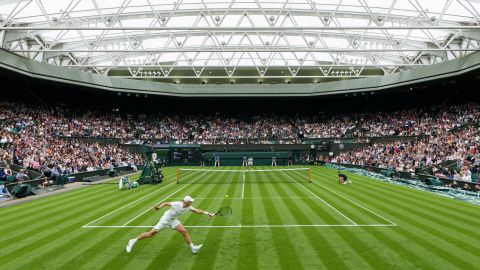 Draper stretches to play a backhand against Djokovic.
