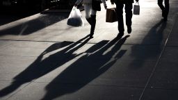 People carrying shopping bags cast shadows while walking in Midtown on December 13, 2020 in New York City. 