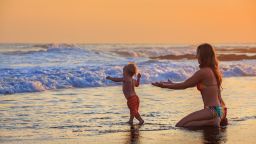 underscored woman and son on beach with ocean waves