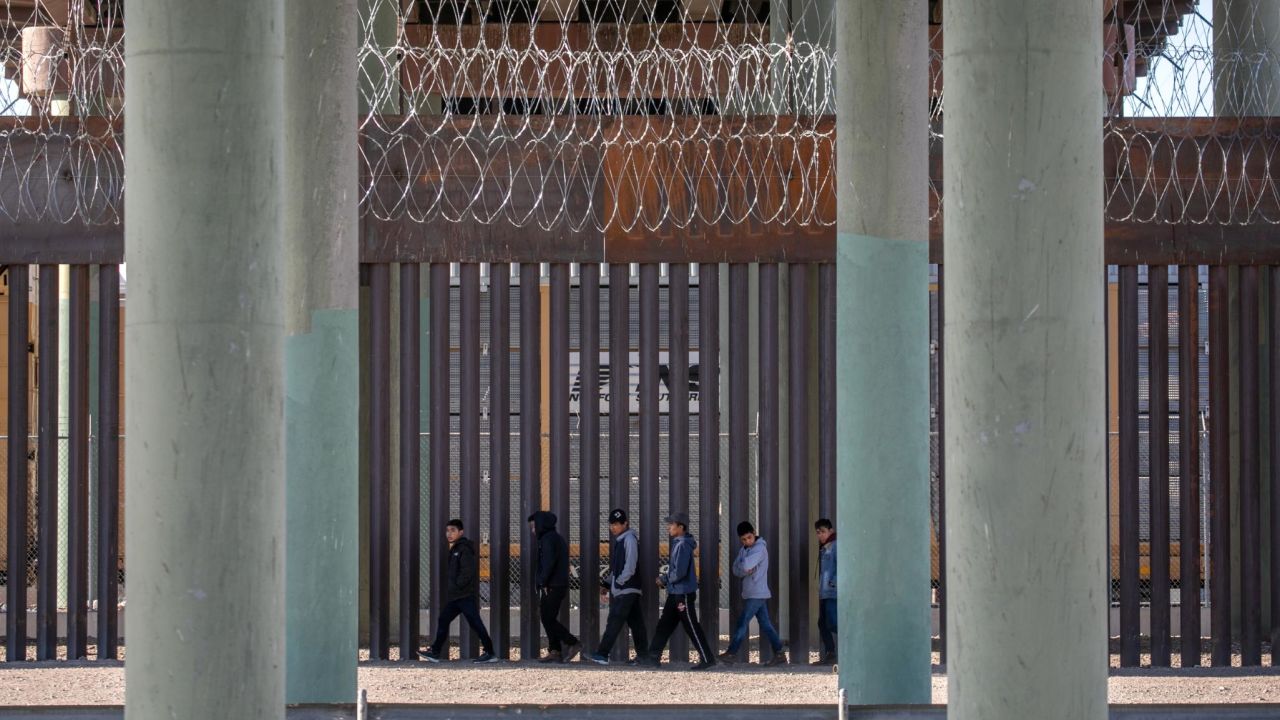 Undocumented immigrants walk along the US-Mexico border wall after they ran across the shallow Rio Grande into El Paso on March 17, 2021, in Ciudad Juarez, Mexico. US immigration officials are dealing with an immigrant surge along the southwest border with Mexico.