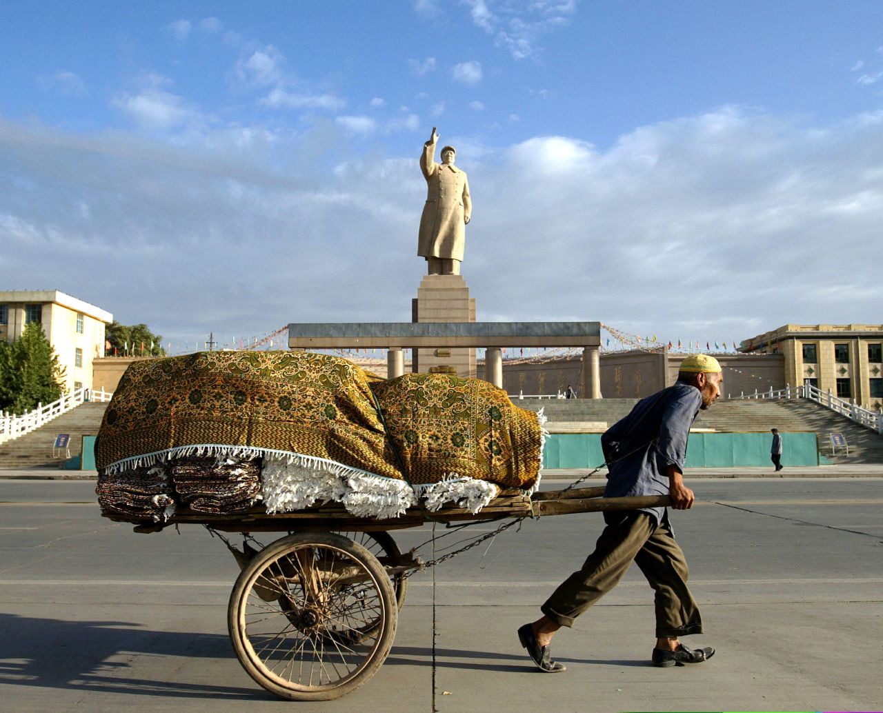 A Uyghur worker pulls a cart past a giant Mao statue at the People's Square in Kashgar, China, in September 2003.