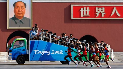 Olympians run past a Mao portrait in Beijing at the start of the men's marathon in 2008.