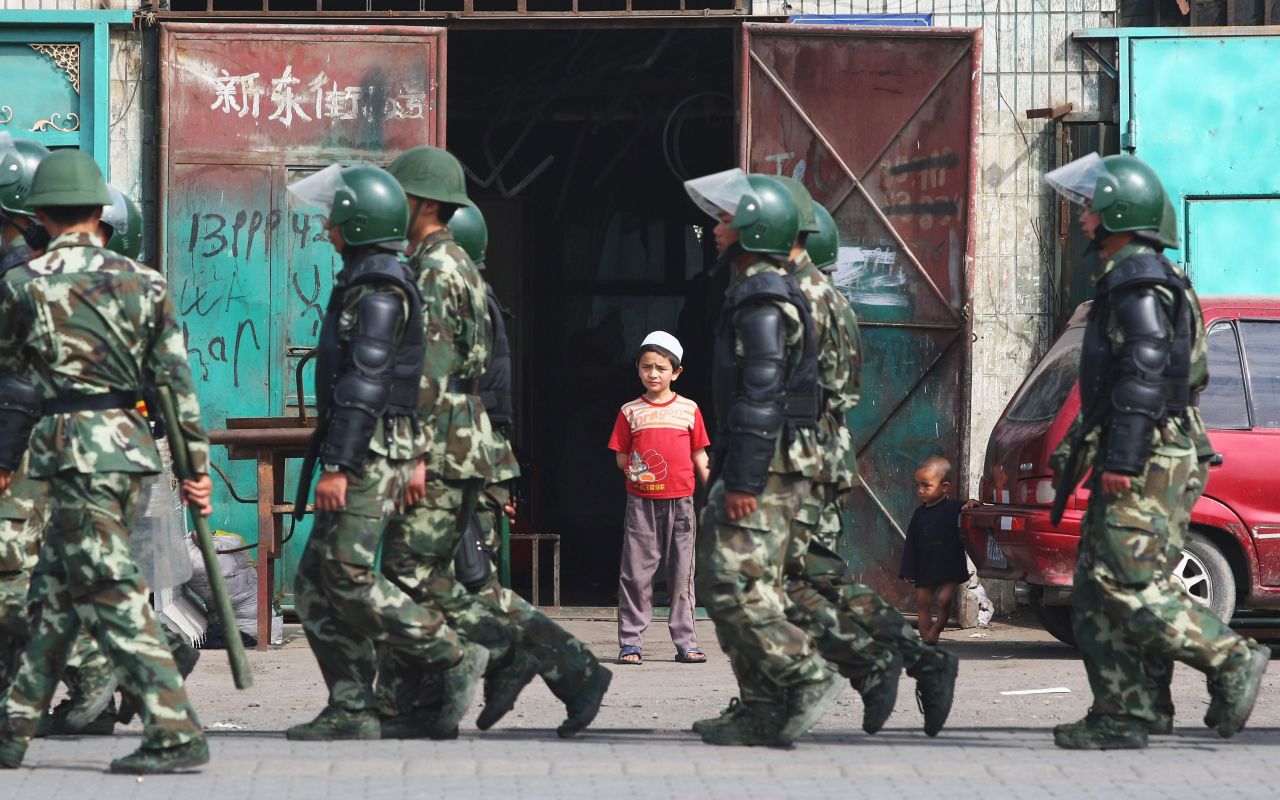 Police pass Uyghur children in Urumqi, the capital of western China's Xinjiang region, while responding to riots on July 7, 2009. The riots were prompted by long-simmering resentment between minority Uyghurs and majority Han Chinese, and about 200 people were killed according to state media. The US State Department and human rights groups have since accused the Chinese government of detaining up to two million Uyghurs and Muslim minorities in extra-legal detention camps, which Beijing claims are "vocational training centers" designed to prevent separatism and religious extremism.