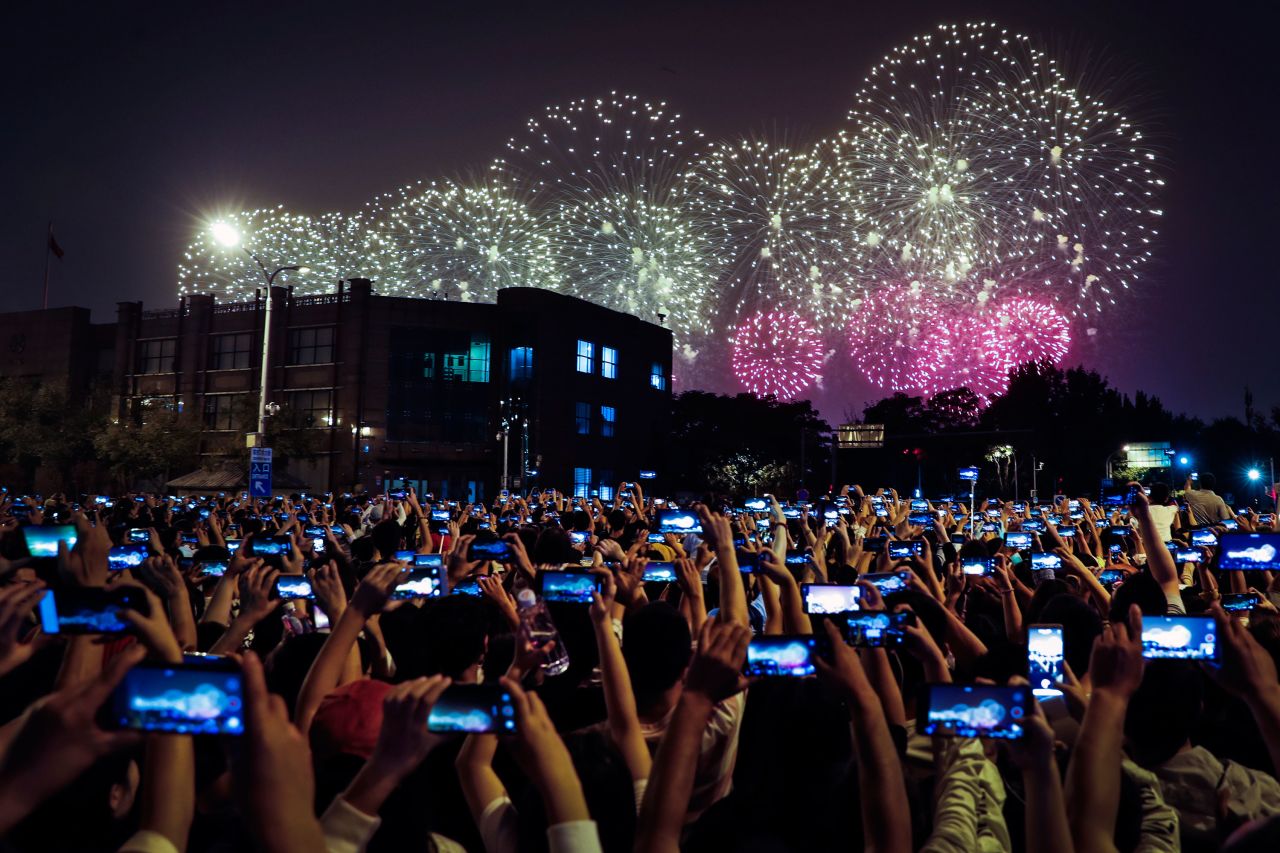 People in Beijing use their cell phones in October 2019 to film fireworks exploding at Tiananmen Square as part of a gala evening commemorating the 70th anniversary of the founding of Communist China.