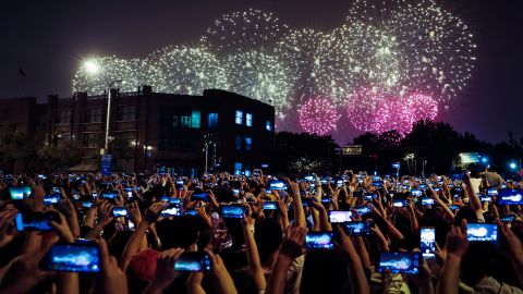 People in Beijing use their cell phones in October 2019 to film fireworks exploding at Tiananmen Square as part of a gala evening commemorating the 70th anniversary of the founding of Communist China.