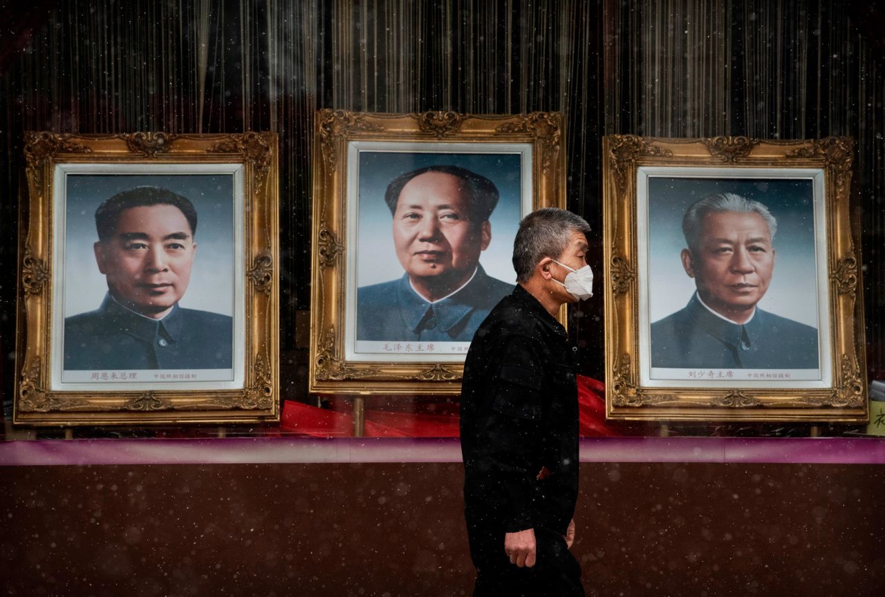 A man wearing a face mask walks by a picture of Mao, center, in a Beijing shopping area that was nearly empty in February 2020. An outbreak of Covid-19 was first reported in Wuhan, a city of 11 million people in central China's Hubei province. The World Health Organization officially called it a pandemic one month later.