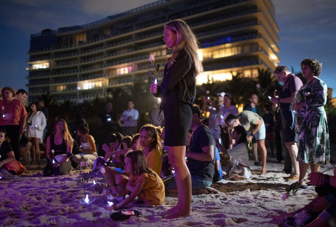 People join together in a community twilight vigil on the beach for those lost and missing during the partially collapsed Champlain Towers South condo building Monday.