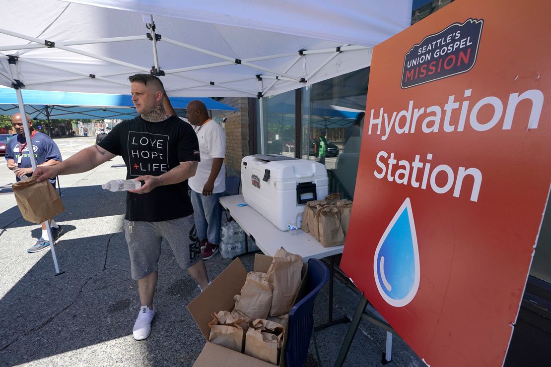 Carlos Ramos hands out bottles of water and sack luncheson Monday at a hydration station in front of the Union Gospel Mission in Seattle.