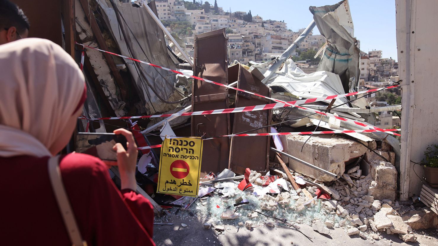 Palestinians stand by the rubble of the demolished shop on Tuesday.