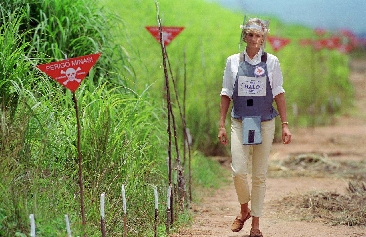 Princess Diana wearing protective body armor, a white shirt and chinos as she walks through a landmine field in Angola. 