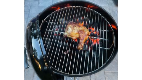 Chicken leg searing on charcoal grill.