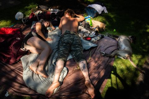 A couple and their dog lie in the shade Monday in Portland, Oregon. Portland had another record-high temperature on Monday: 116 degrees.