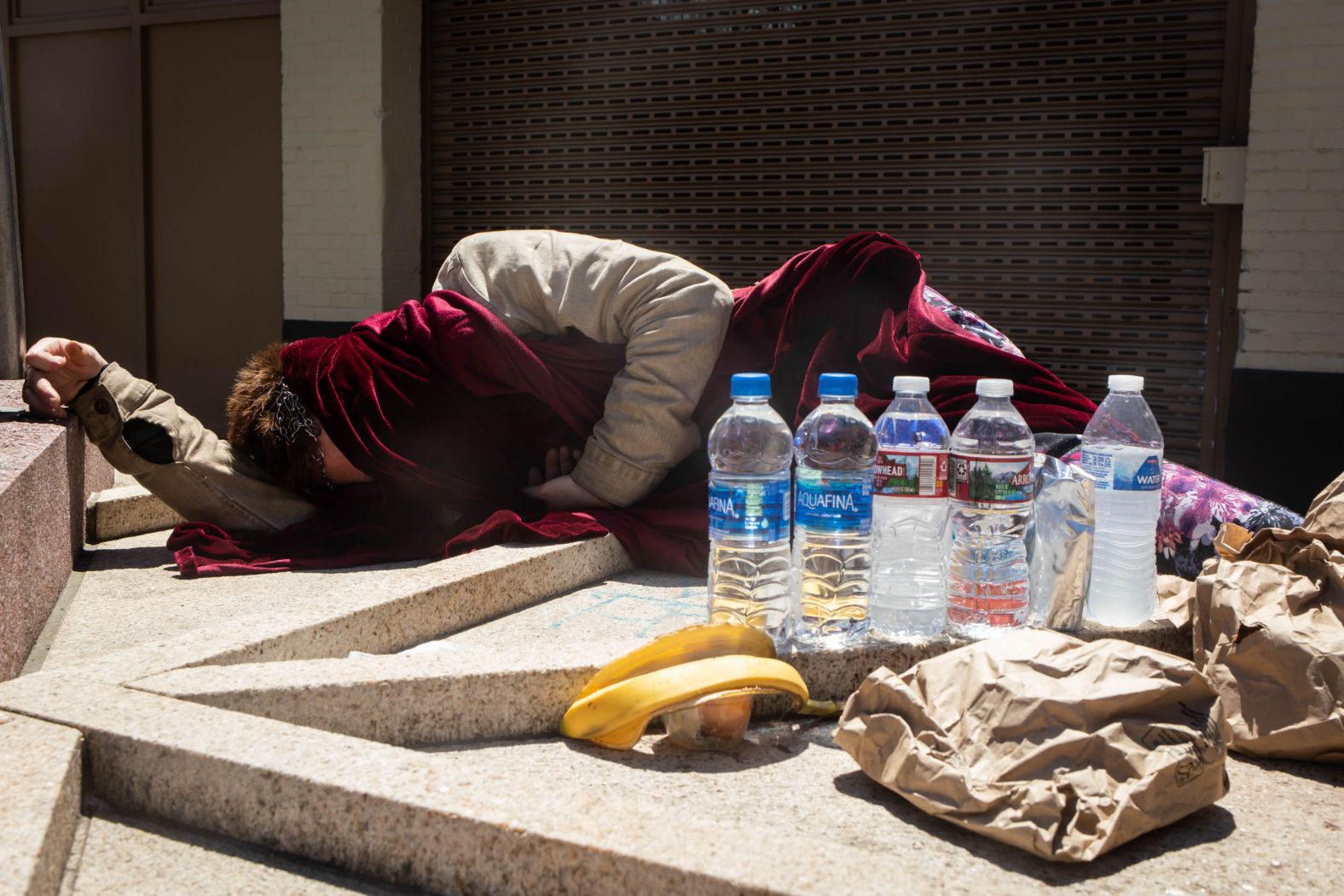 A man experiencing homelessness sleeps in the Portland sun on Monday. Nonprofit groups have also been opening cooling centers to help people in Portland and other Oregon cities.