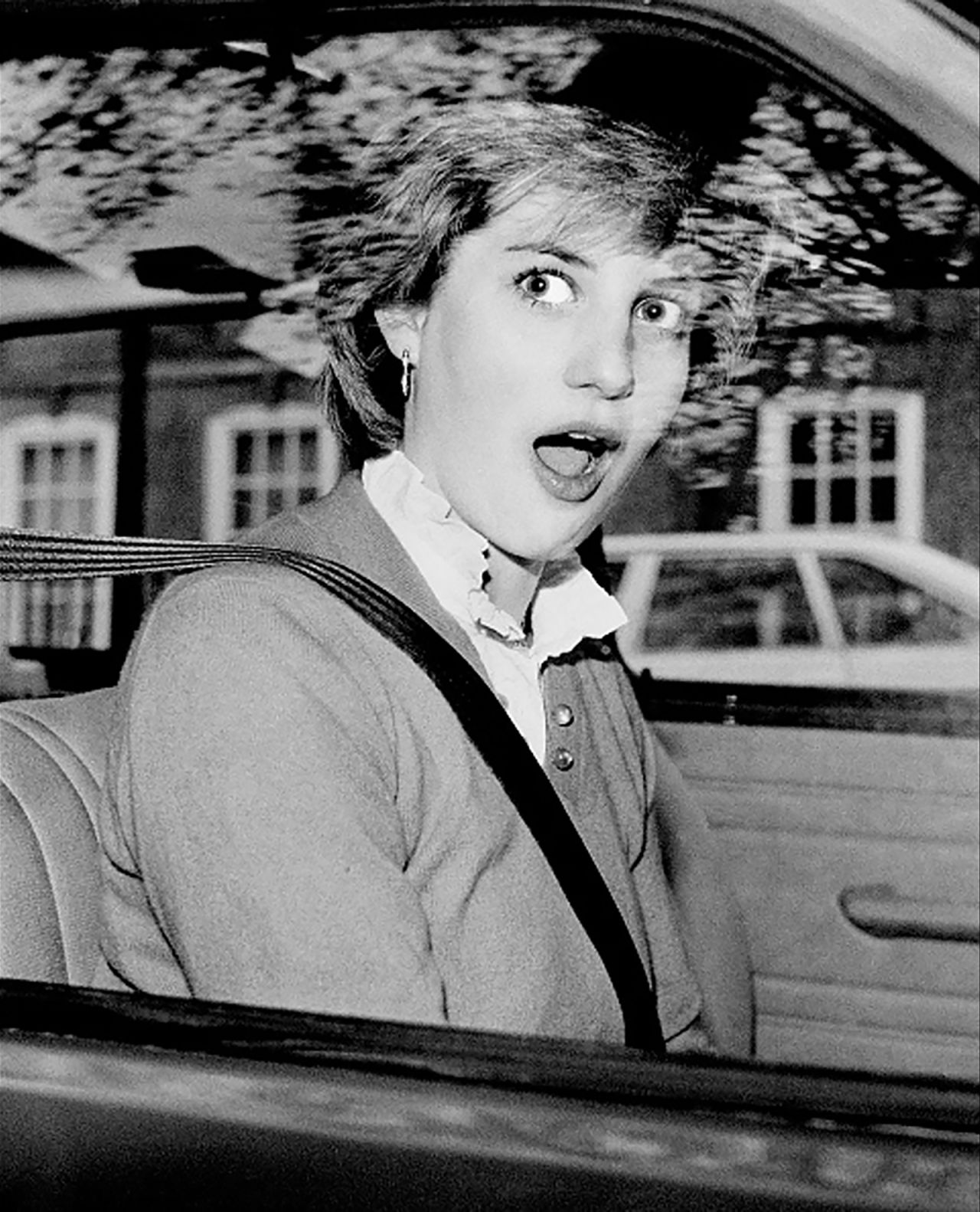 Diana looks startled after stalling her new car outside her London apartment in November 1980. 