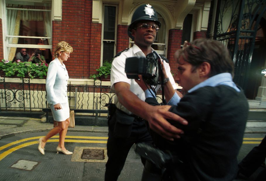 A police officer holds back a photographer as Diana walks by in July 1996. It had just been announced that Diana and Charles had divorced. 