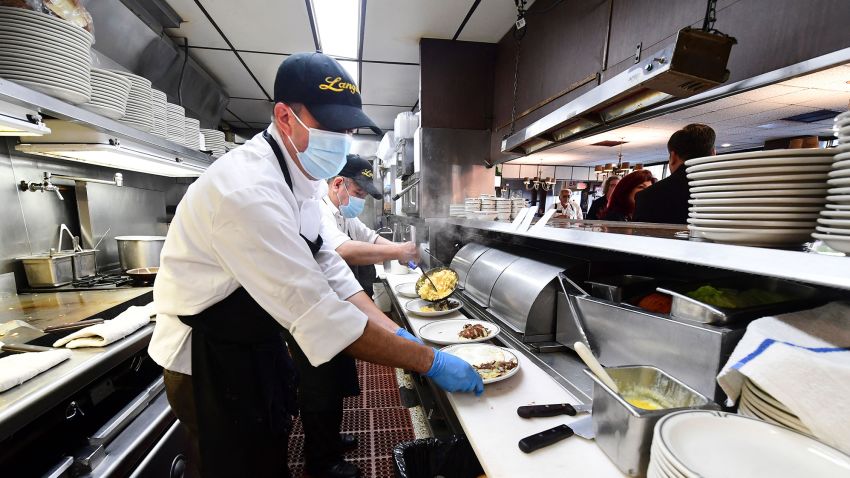 In this photo taken on June 15, 2021 kitchen staff continue wearing facemasks while preparing breakfast at Langer's Delicatessen-Restaurant in Los Angeles, California, on California's first day of fully reopening its economy after some fifteen months of Coronavirus pandemic restrictions.