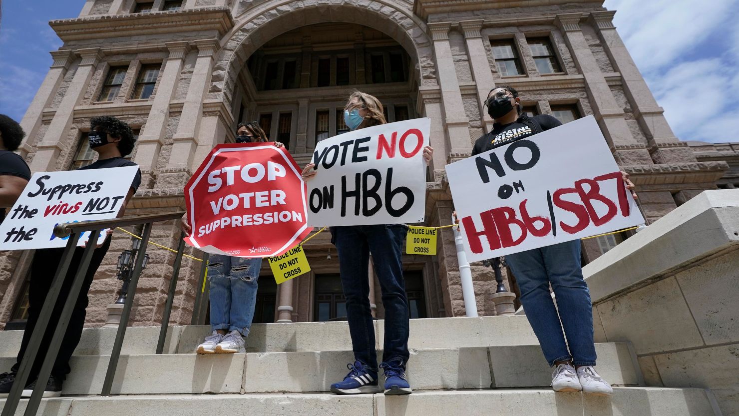 People opposed to Texas voter bills HB6 and SB7 hold signs during a news conference on the steps of the State Capitol in Austin, Texas in April 2021.