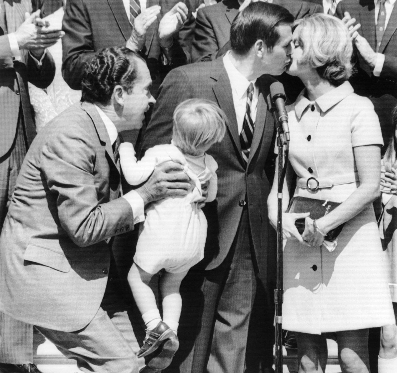 Rumsfeld is kissed by his wife, Joyce, after he was sworn in as director of the Office of Economic Opportunity in 1969. President Richard Nixon is holding their 2-year-old son, Nicholas.