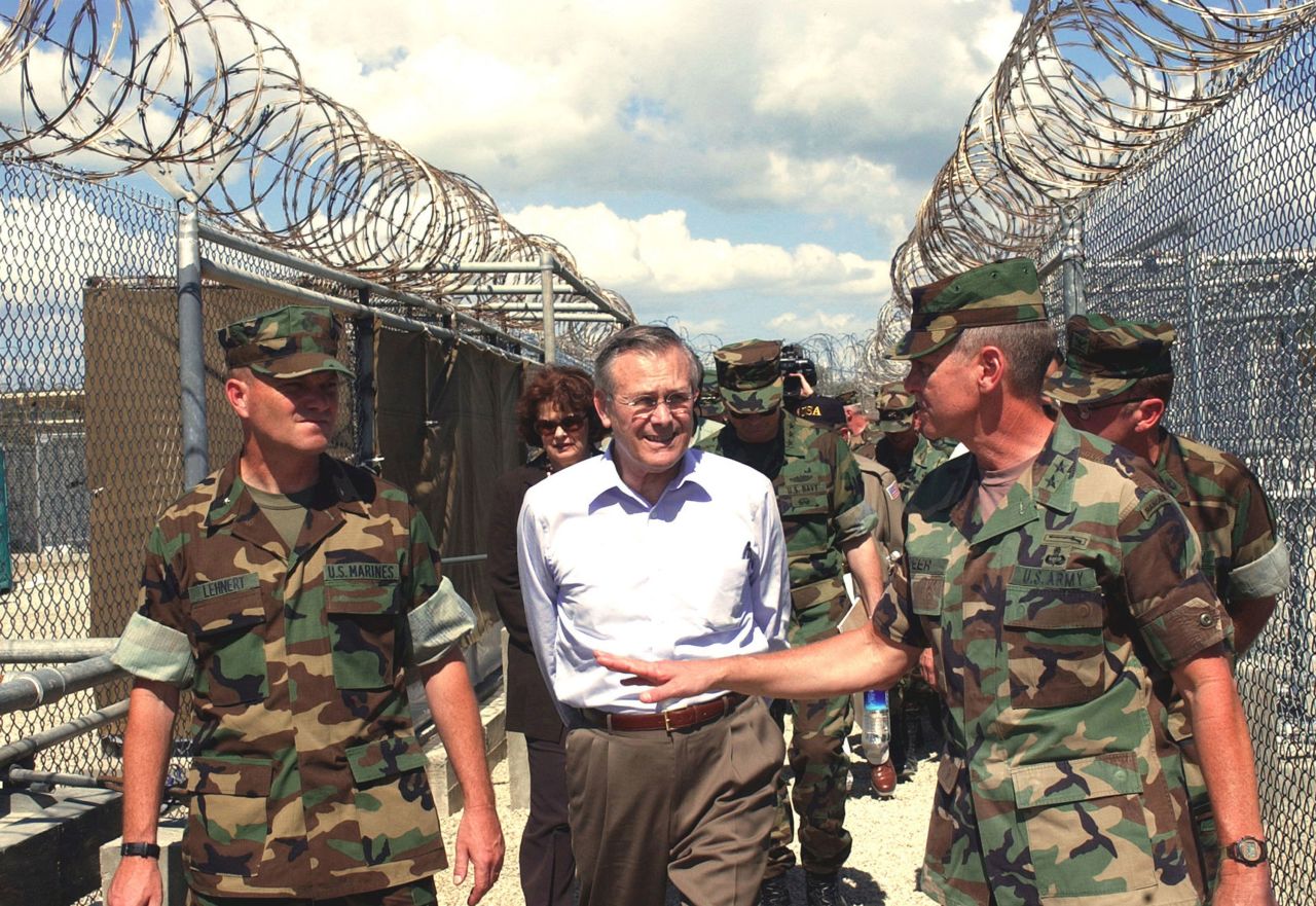 Rumsfeld tours the detention facility Camp X-Ray while visiting Guantanamo Bay, Cuba, in 2002. Rumsfeld said that the Taliban and al Qaeda prisoners being held at the base would not be given prisoner-of-war status.