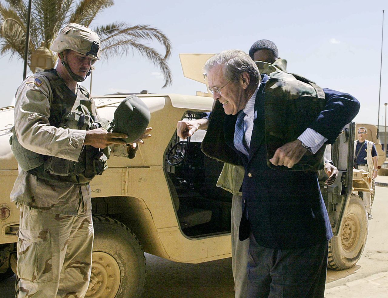 Rumsfeld puts on a bulletproof jacket while visiting Baghdad, Iraq, in April 2003.
