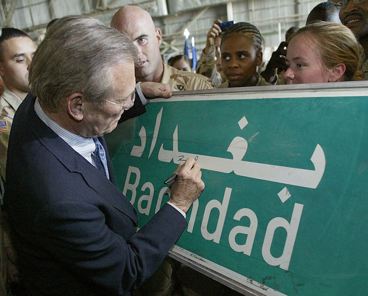 Rumsfeld signs a Baghdad road sign at the request of a US soldier in April 2003.