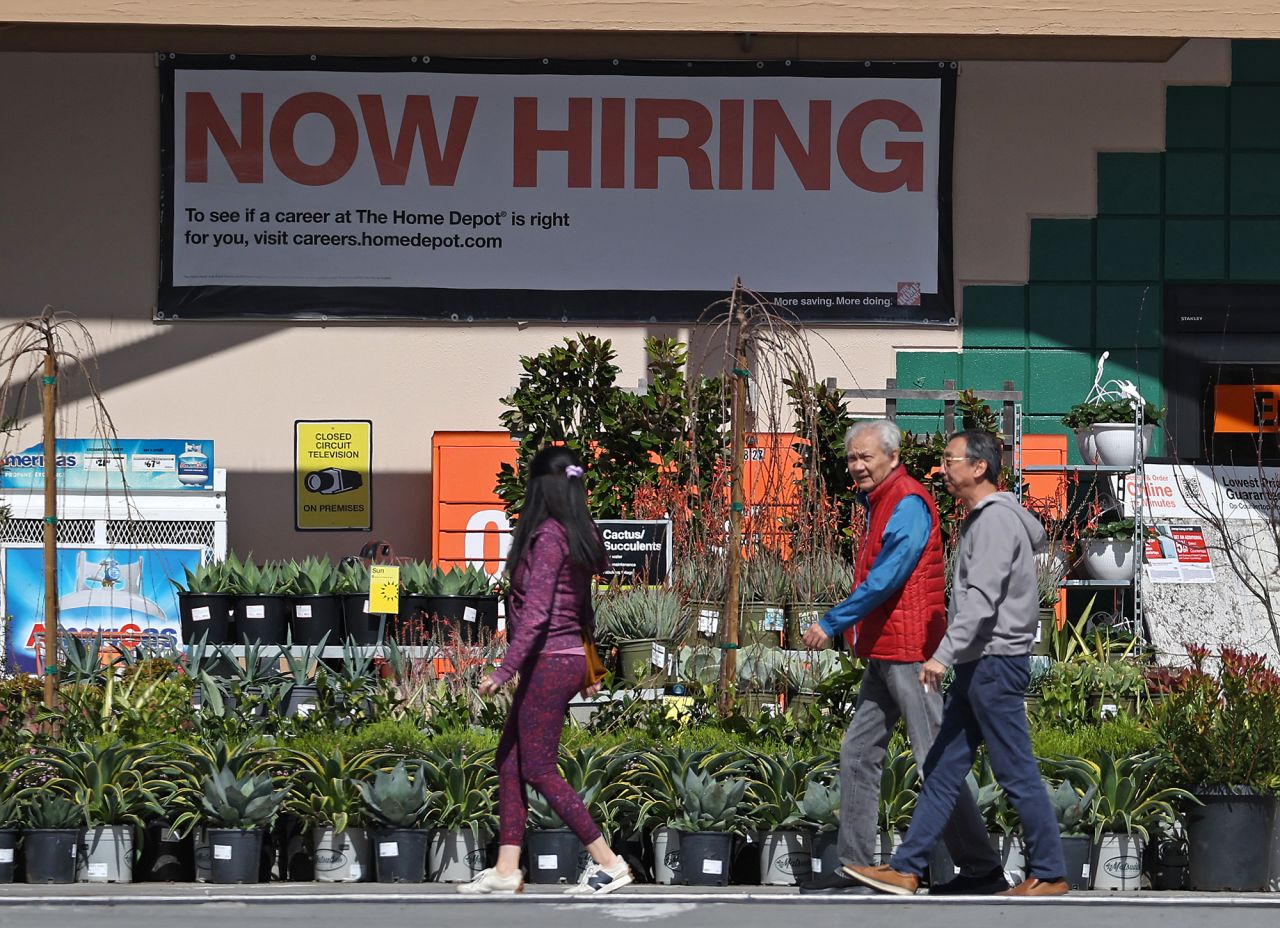 People walk by a posted "Now hiring" sign on March 8 in San Rafael, California. 