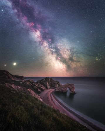 The Milky Way is rising over Durdle Door, southern England, and Saturn and Jupiter can also be seen to the left of the frame, just above the horizon.