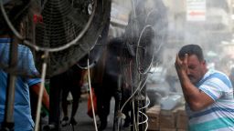 A man stands by fans spraying air mixed with water vapour deployed by donors to cool down pedestrians along a street in Iraq's capital Baghdad on June 30, 2021 amidst a severe heat wave. (Photo by AHMAD AL-RUBAYE / AFP) (Photo by AHMAD AL-RUBAYE/AFP via Getty Images)