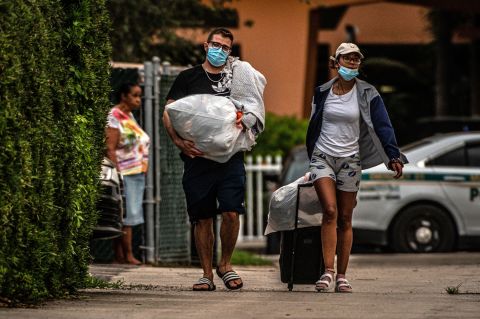 Residents of the Crestview Towers Condominium carry their belongings <a href=