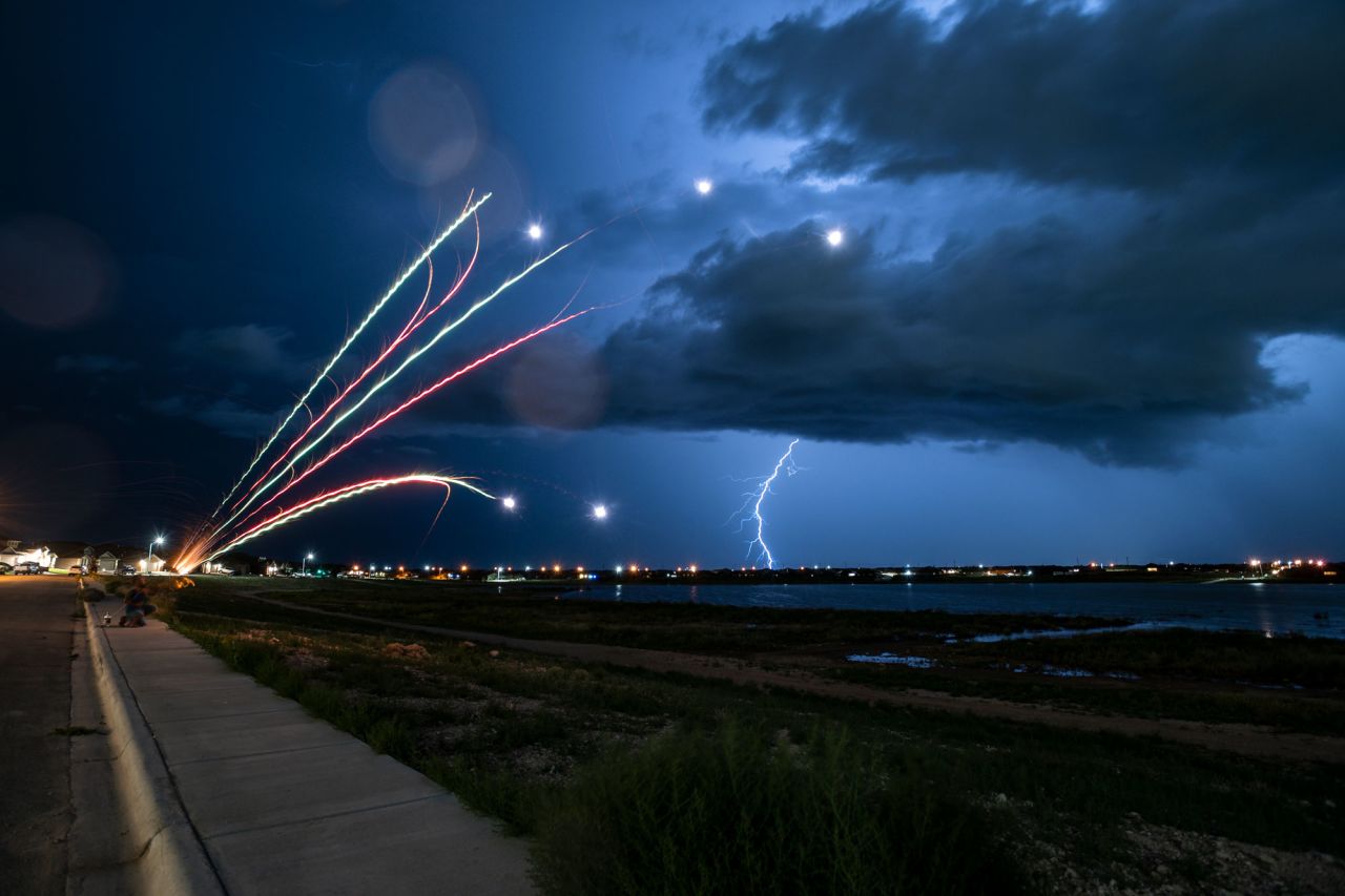 Bobby Florez lights fireworks with his nephew Kaden Perez, 5, as a lightning storm passes by in the distance Friday night, July 2, in Odessa, Texas.