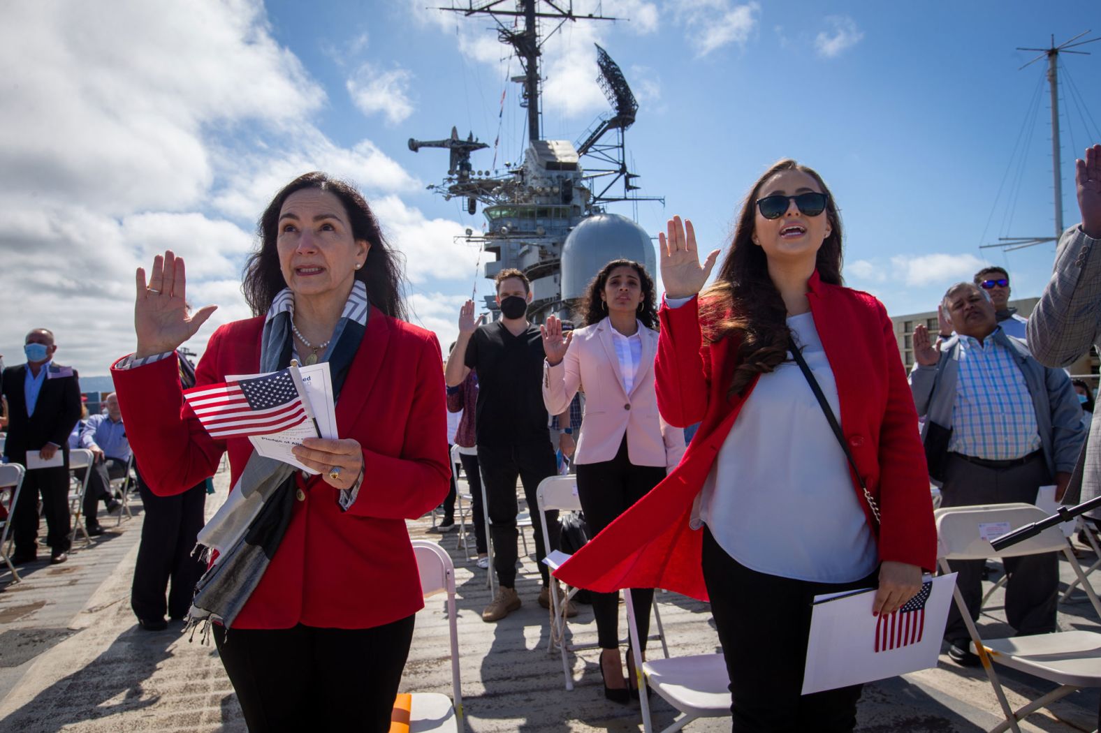 Maria Laura Limpias Chavez, left, of Bolivia, Sahara Loffsner, of Colombia, and fellow new American citizens, take the Oath of Allegiance during a naturalization ceremony on the flight deck of the USS Hornet Museum in Alameda, California, on Friday, July 2.
