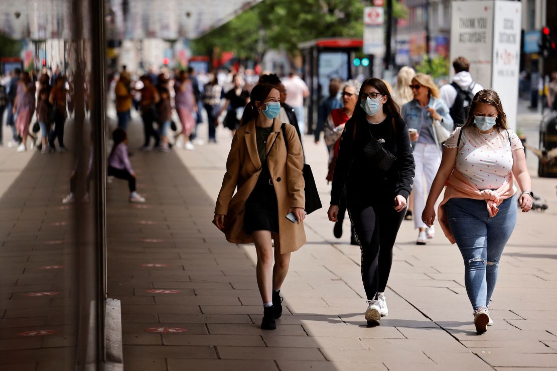 Pedestrians wearing a face mask or covering due to the COVID-19 pandemic, walk along Oxford Street in central London on June 6.