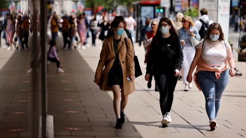 Pedestrians wearing a face mask or covering due to the COVID-19 pandemic, walk along Oxford Street in central London on June 6.