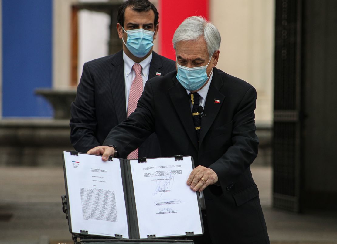 Chilean President Sebastian Pinera shows the official document that calls on the National Assembly members that will draft a new constitution to meet for their first session on July 4, at La Moneda presidential palace in Santiago, Chile, Sunday, June 20, 2021.