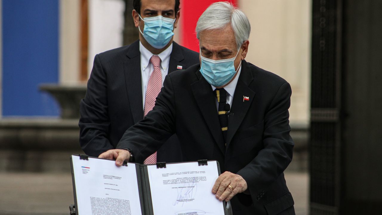 Chilean President Sebastian Pinera shows the official document that calls on the National Assembly members that will draft a new constitution to meet for their first session on July 4, at La Moneda presidential palace in Santiago, Chile, Sunday, June 20, 2021.