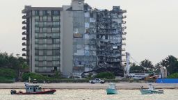 A U.S. Coast Guard, left, and a Miami-Dade County Police boat, right, patrol the ocean in front of the partially collapsed Champlain Towers South condo building, where demolition experts were preparing to bring down the precarious still-standing portion.