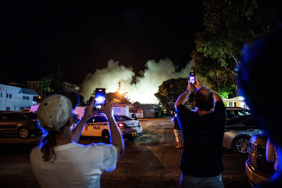 People watch a cloud of dust form as the rest of the building is demolished.