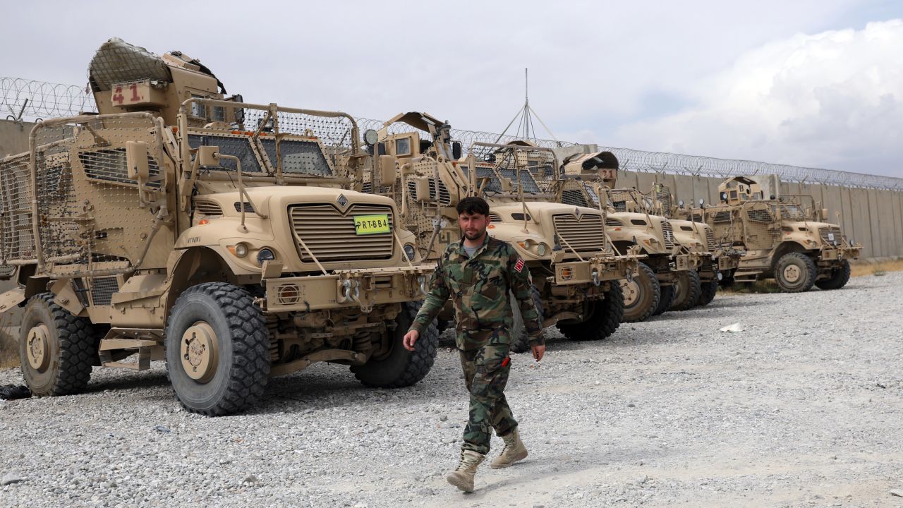An Afghan army soldier walks past Mine Resistant Ambush Protected vehicles, MRAP, that were left after the American military left Bagram air base, in Parwan province north of Kabul, Afghanistan, Monday, July 5, 2021. 