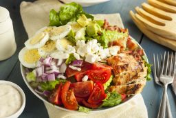 This hearty Cobb salad features chicken, bacon, t tomato, onions and eggs.