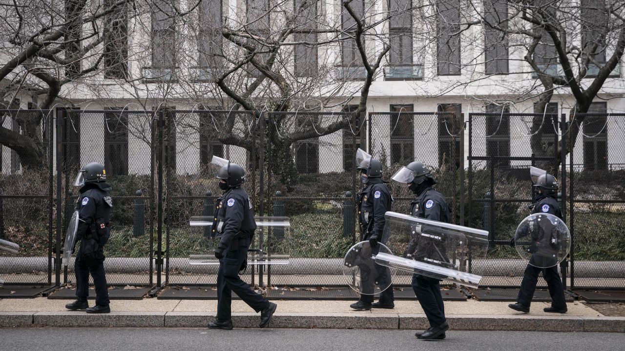 US Capitol police officers in protective riot gear walk by the fenced perimeter of the U.S. Capitol grounds in Washington, D.C., on Friday, January 29, 2021. 