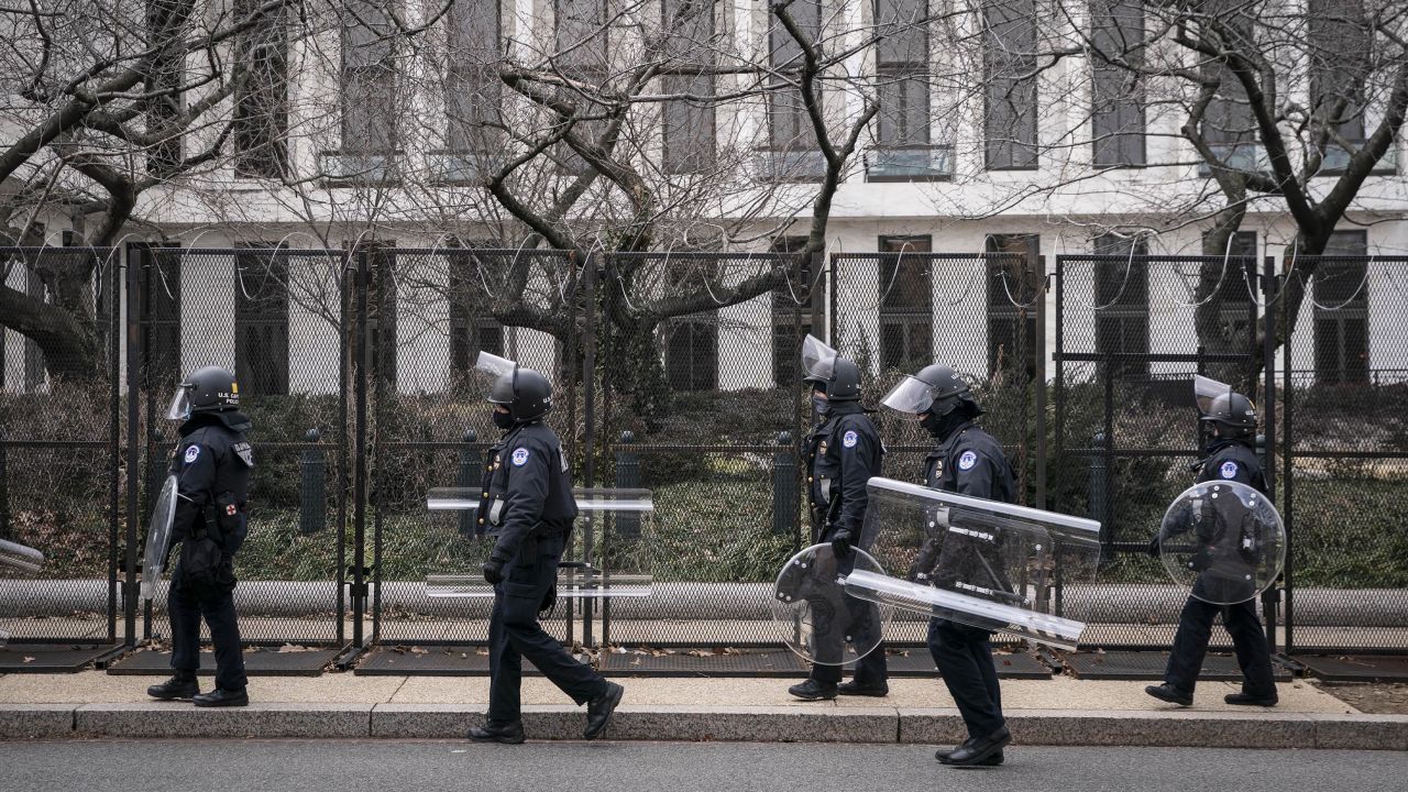 US Capitol police officers in protective riot gear walk by the fenced perimeter of the U.S. Capitol grounds in Washington, D.C., on Friday, January 29, 2021.