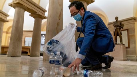 Rep. Andy Kim, a Democrat from New Jersey, cleans up debris and trash strewn across the floor in the early morning hours of January 7, after protesters stormed the Capitol in Washington, on Wednesday. 