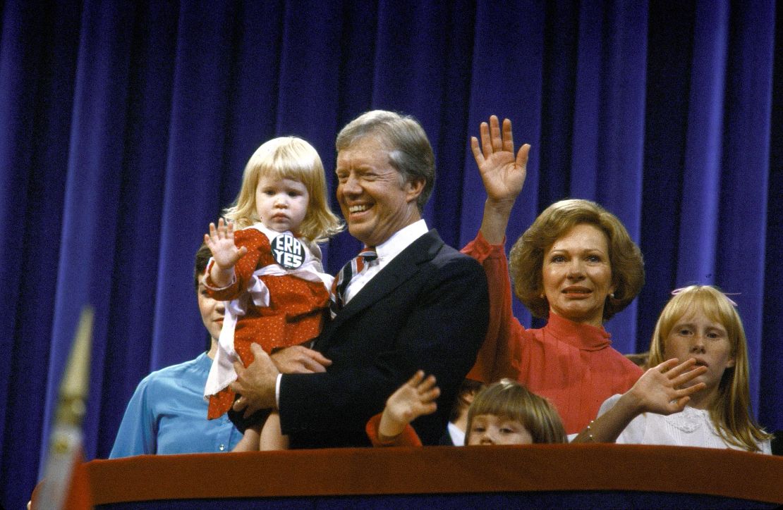 Then-President Jimmy Carter holding his granddaughter Sarah, being flanked by his wife Rosalynn and daughter Amy, at the Democratic National Convention.