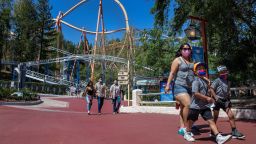 Diana Navarro, 27, of Baldwin Park, and her sons, Moises, 7, left, and Mason, 6, make their way inside Six Flags Magic Mountain in Valencia on April 2, 2021.