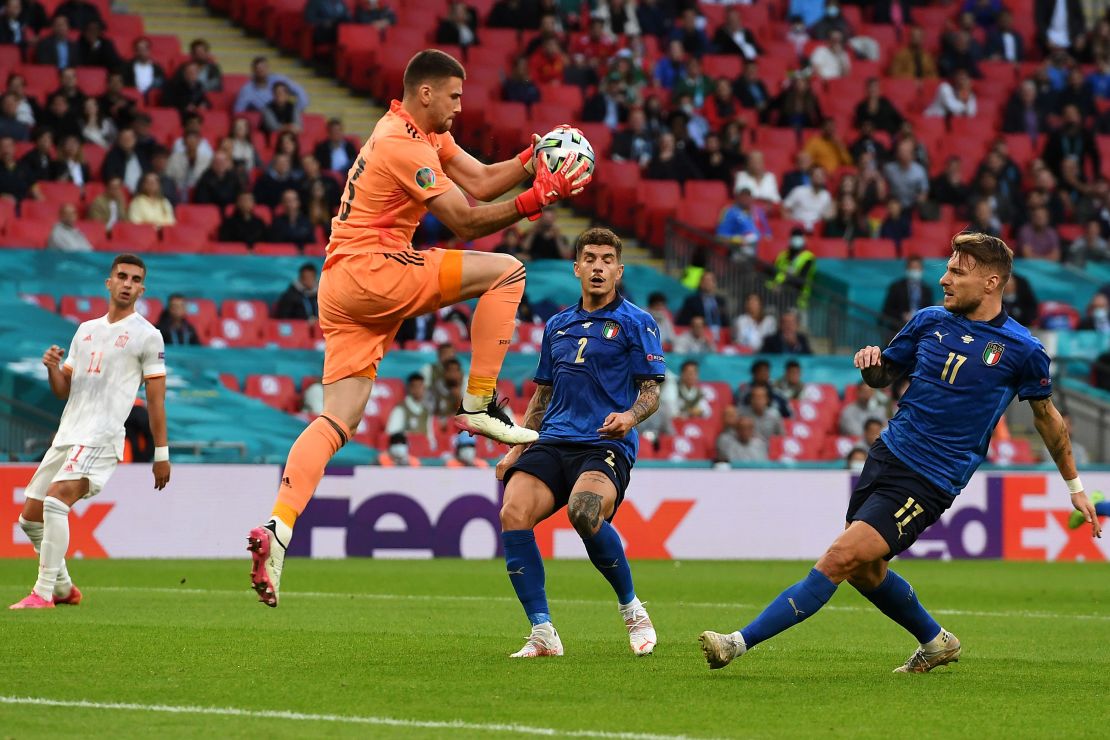 Spain goalkeeper Unai Simon makes a save whilst under pressure from Ciro Immobile.